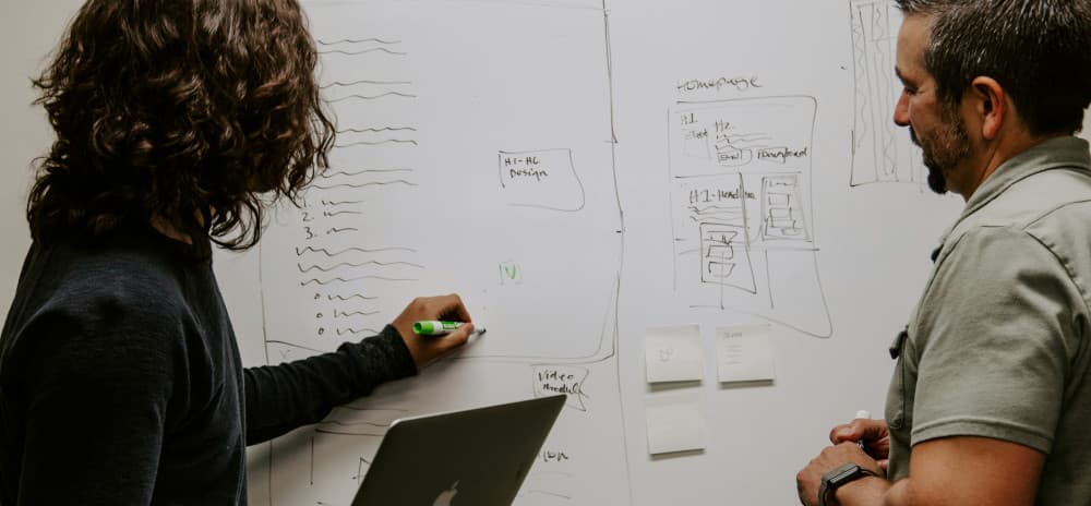 Two people mapping a current-state process on a whiteboard